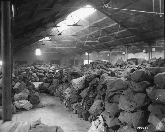 Warehouse full of sacks of large sacks of mail piled 6 or 7 feet high.