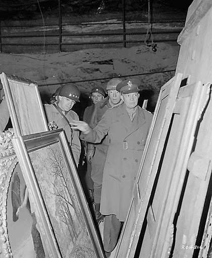 Soldiers inspect stacks of framed paintings