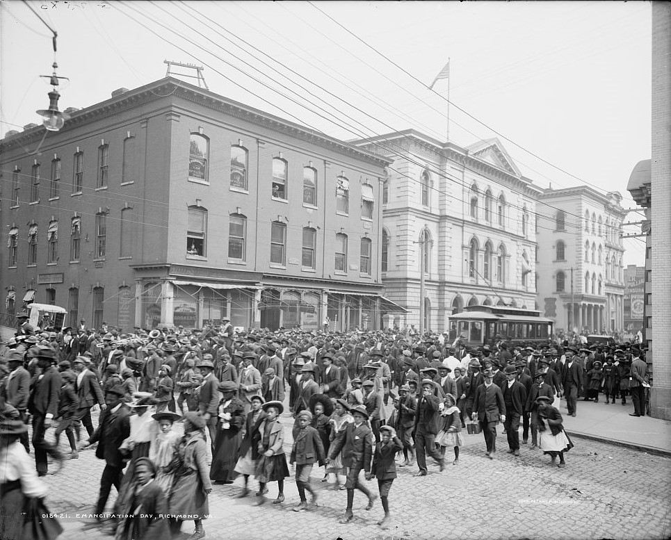 Large group of Black citizens parading down a street. 