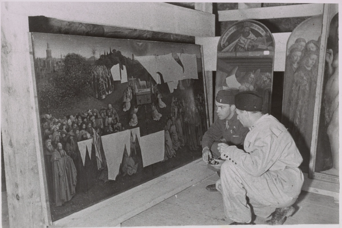 two men crouching to examine one panel of the Ghent Altarpiece or Adoration of the mystic lamb by Jan van Eyck.